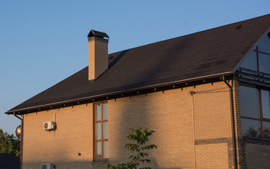 Modern brick house with rectangular window and air-conditioner, chimney under blue sky