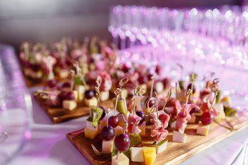 the buffet at the reception. Glasses of wine and champagne. Assortment of canapes on wooden board. Banquet service. catering food, snacks with cheese, jamon, prosciutto and fruit