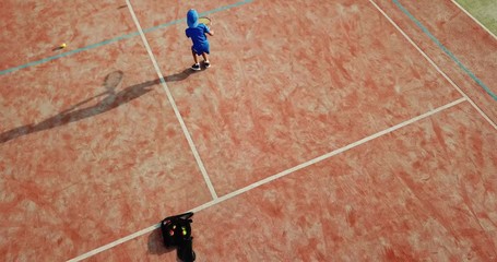 Little boy playing tennis. Little boy in tennis serving. Aerial view.
