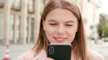 A happy smiling lady using a phone in the city street. Close-up shot. Soft focus