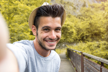 Portrait of handsome caucasian man taking a selfie on vacation on a nature background