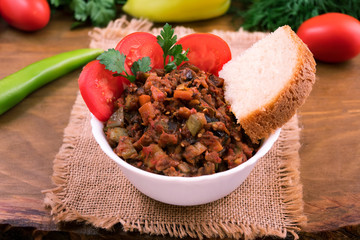 Vegetable stew with bread, sliced tomatoes and parsley in a white round bowl.