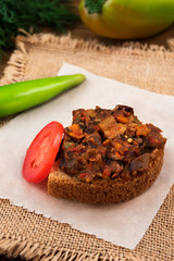 Sandwich of white bread and stewed vegetables with a slice of tomato and bitter pepper.