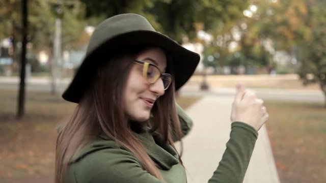 A cheerful girl in a park in autumn, calling a friend. Emotion, a girl in a hat and glasses