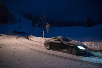 car driving on dangerous road at night on snow