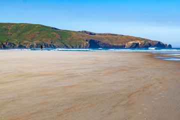 Person walking on beach towards the hills