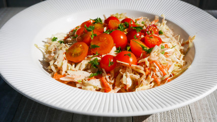 A white bowl with cole slaw with cherry tomatoes atop