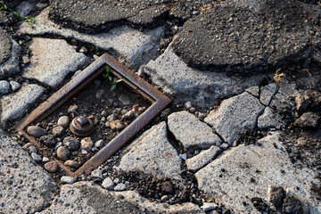 Cracked broken distressed pavement with broken utility hook up