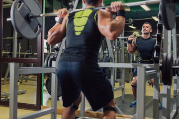 Man doing squats in the gym in front of a mirror