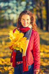 Young beautiful woman enjoys sunny autumn day in the park