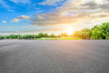 Empty asphalt road and green forest with colorful clouds at sunset