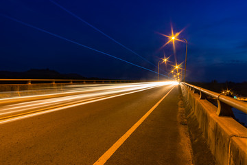 Traffic light trails at night on a bridge.
