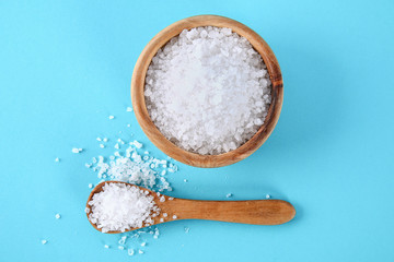 Fototapeta na wymiar Crystals of large sea salt in a wooden bowl and spoon on a blue table.