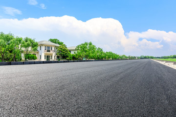 Fototapeta premium Empty asphalt road and forest with apartment buildings in the city suburbs