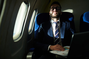 Fototapeta na wymiar Portrait of successful businessman sleeping during long flight in dimly lit plane, copy space