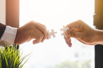 Teamwork, partners, connection concept. Hands of two businessmen merging jigsaw puzzle on the...