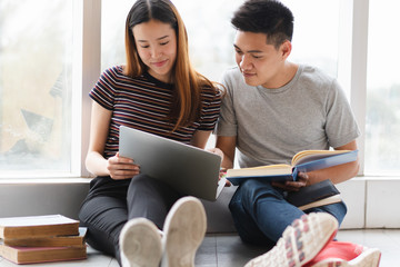 Two asian students researching for project in library.