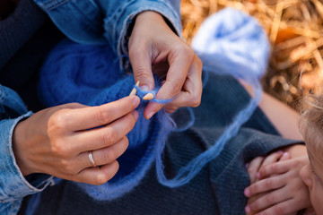 Concept of a freelancer work in the open air. Close up  of a young woman in a denim jacket knitting...