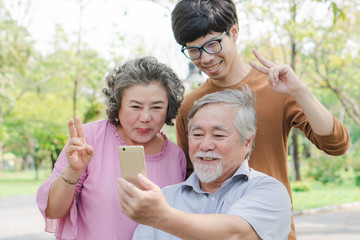 Happy elderly with family. Grandpa and grandma using mobile phone taking photo with grandson