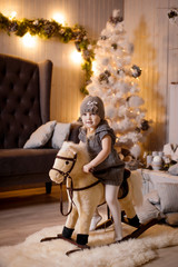 A little pretty girl celebrates a new year or Christmas in a cozy interior. Portrait of a girl on a Christmas decor background.