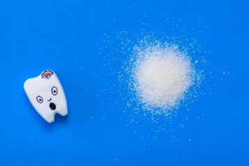 A figure of a frightened tooth and a pile of sugar on a blue background.