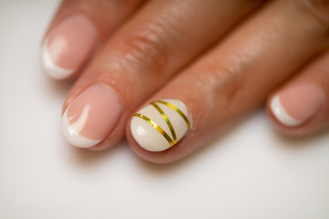 French manicure and nail gel Polish. The decoration of the nail white and gold decor. Top view Close-up photography