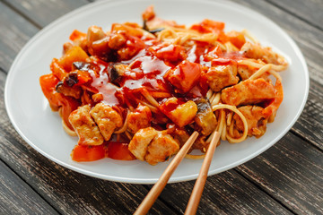 udon noodle with chicken and vegetables in a white plate close up