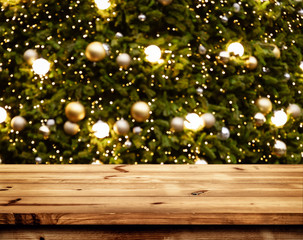 Christmas and New year background with empty wooden deck table over blurred christmas tree at night. Empty display for product montage. Rustic scene.