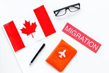 Immigration to Canada concept. Text immigration near passport cover and canadianflag on white...