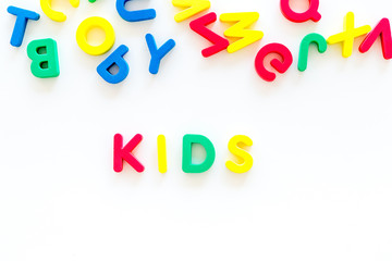 Early childhood development concept. Word kids written by plastic letters of toy alphabet on white background top view copy space