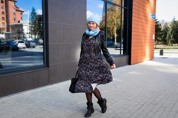 Portrait of a beautiful young model in blue knitted hat standing do to work, on background gray...