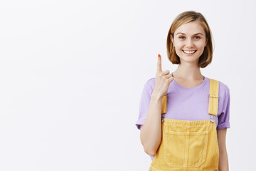 Give me one sec. Charming relaxed and carefree female with fair hair, showing index finger and...