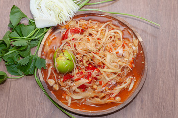 spicy papaya salad or Som Tum in Thailand on wooden plate with vegetable