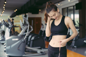 Young beautiful woman athlete using body fat measurement and waist size with waist line after workout at fitness gym healthy lifestyle weightloss happy in goal.