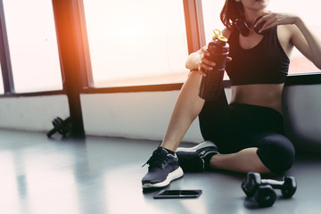 Woman exercise workout in gym fitness breaking relax holding protein shake bottle after training...