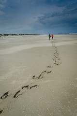footsteps on the beach, couple waling on the soft sand. Dark sky in the background