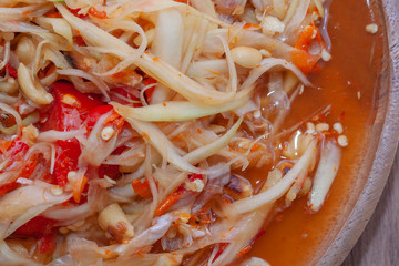 spicy papaya salad or Som Tum in Thailand on wooden plate with vegetable