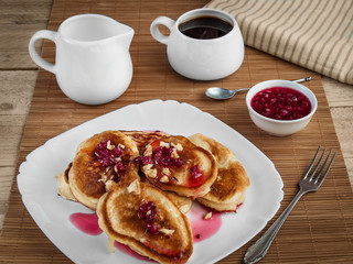 Pancakes stuffed with jam and sprinkled with walnuts lie on a white plate