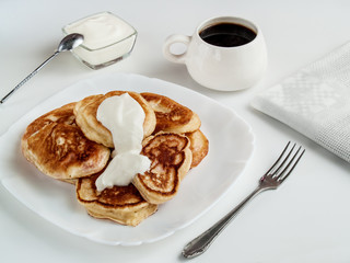 Pancakes stuffed with sour cream lie on a white plate