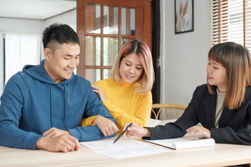 Asian couple listening to realtor agent explaination about house plan with home contract on table.buying new apartment real estate.