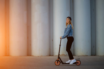Happy young woman rides a scooter in the Park