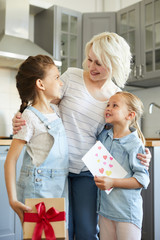 Happy young woman and her two little daughters with gifts looking at each other