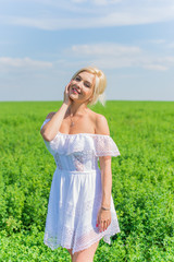 Fototapeta na wymiar Freedom concept. Young happy woman in green field, evening light. Blue sky behind. Beauty Girl Outdoors enjoying nature. Beautiful Model girl in white dress running on the meadow 