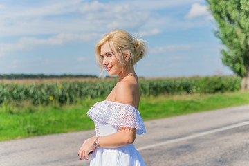 Fototapeta premium Freedom concept. Young happy woman in green field, evening light. Blue sky behind. Beauty Girl Outdoors enjoying nature. Beautiful Model girl in white dress running on the meadow 