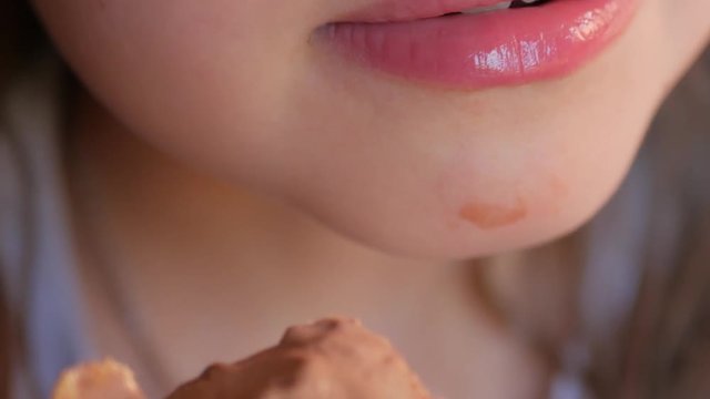 Baby mouth bites chocolate ice cream close-up.