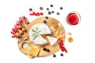 An overhead photo of Camembert cheese with a glass of red wine, fruits and nuts, shot from above on a white background with copy space © laplateresca