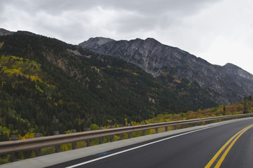 A long wet road running along side the granite mountain range in utah. 