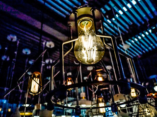 Tungsten orange light bulb hanging on the inside of the building with a black iron fence around,Lighting in buildings with multi-colored electric lamps,soft focus.