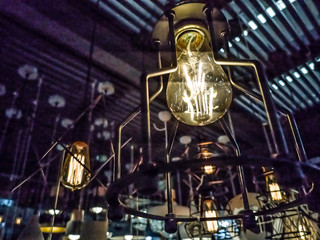 Tungsten orange light bulb hanging on the inside of the building with a black iron fence around,Lighting in buildings with multi-colored electric lamps,soft focus.