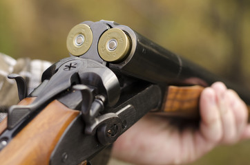 The twelve-gauge two-barrelled loaded coachgun in man's hands